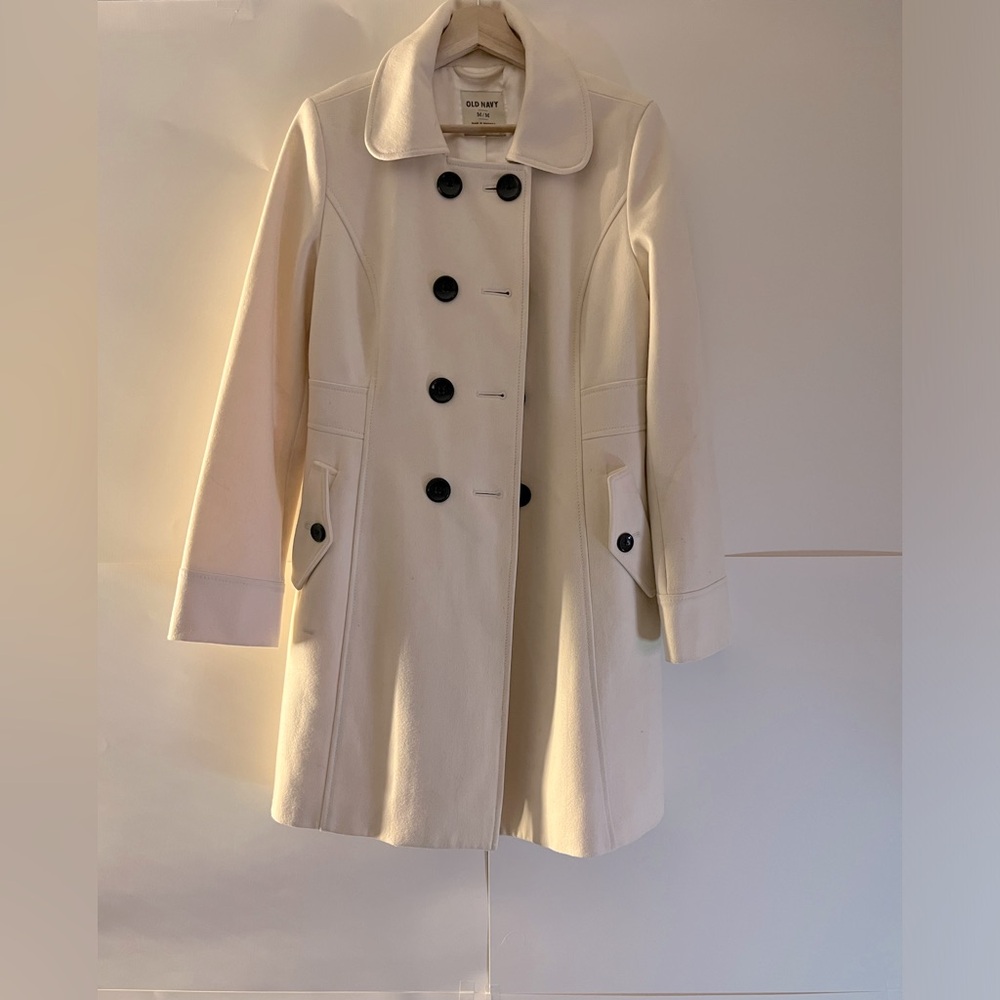 Thick white long cream pea coat with black buttons.